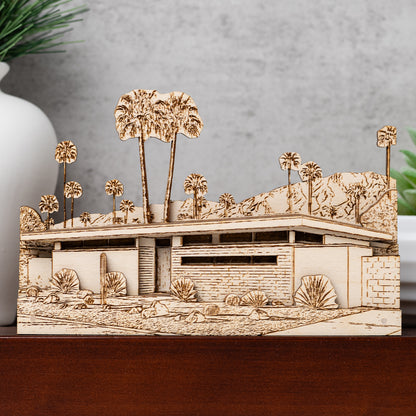 Wooden model of a desert home with buildings and palm trees on a gray background
