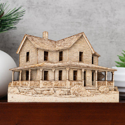 Wooden model of a two-story house with a porch on a wooden surface.