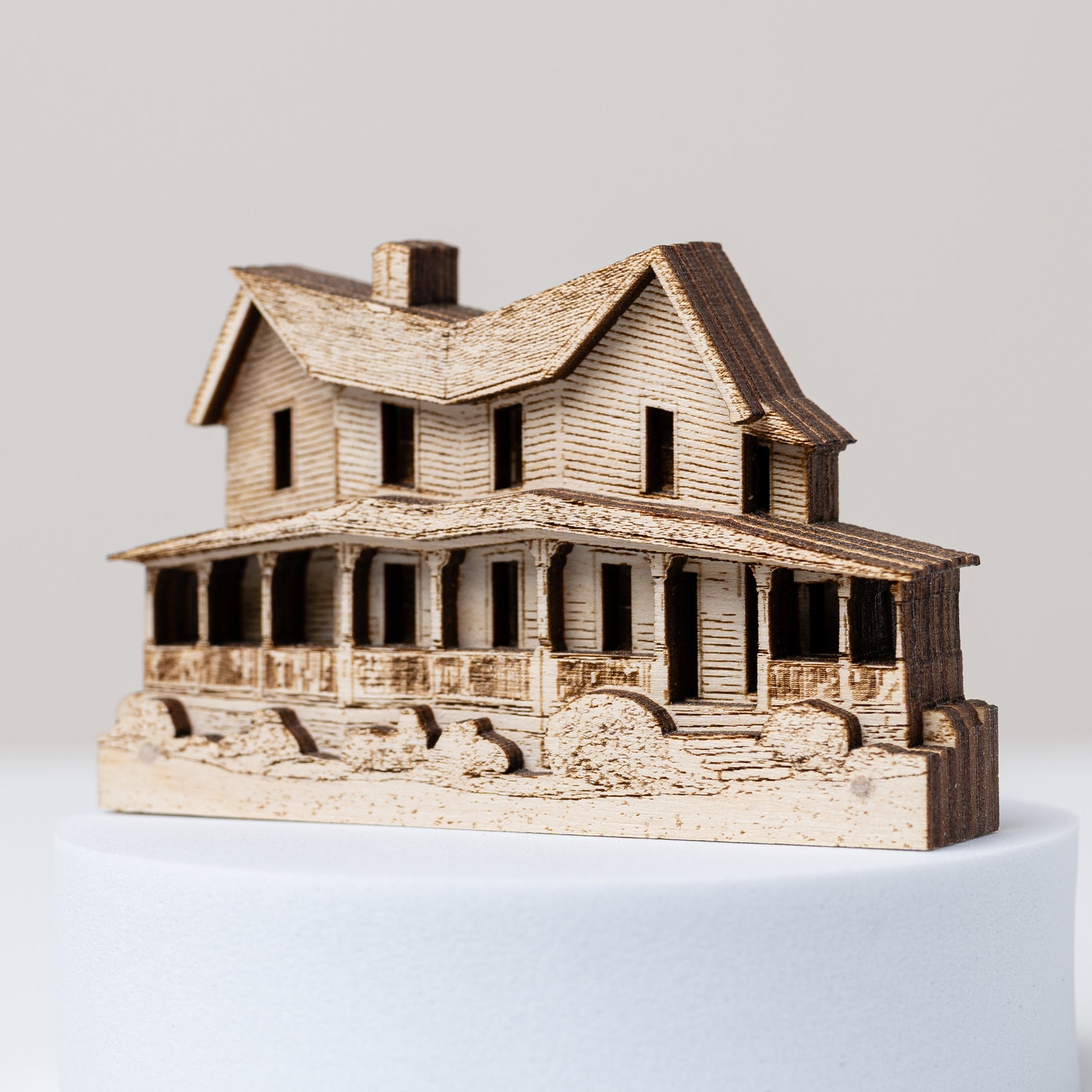 Wooden model of a house angled to show its layering on a white background